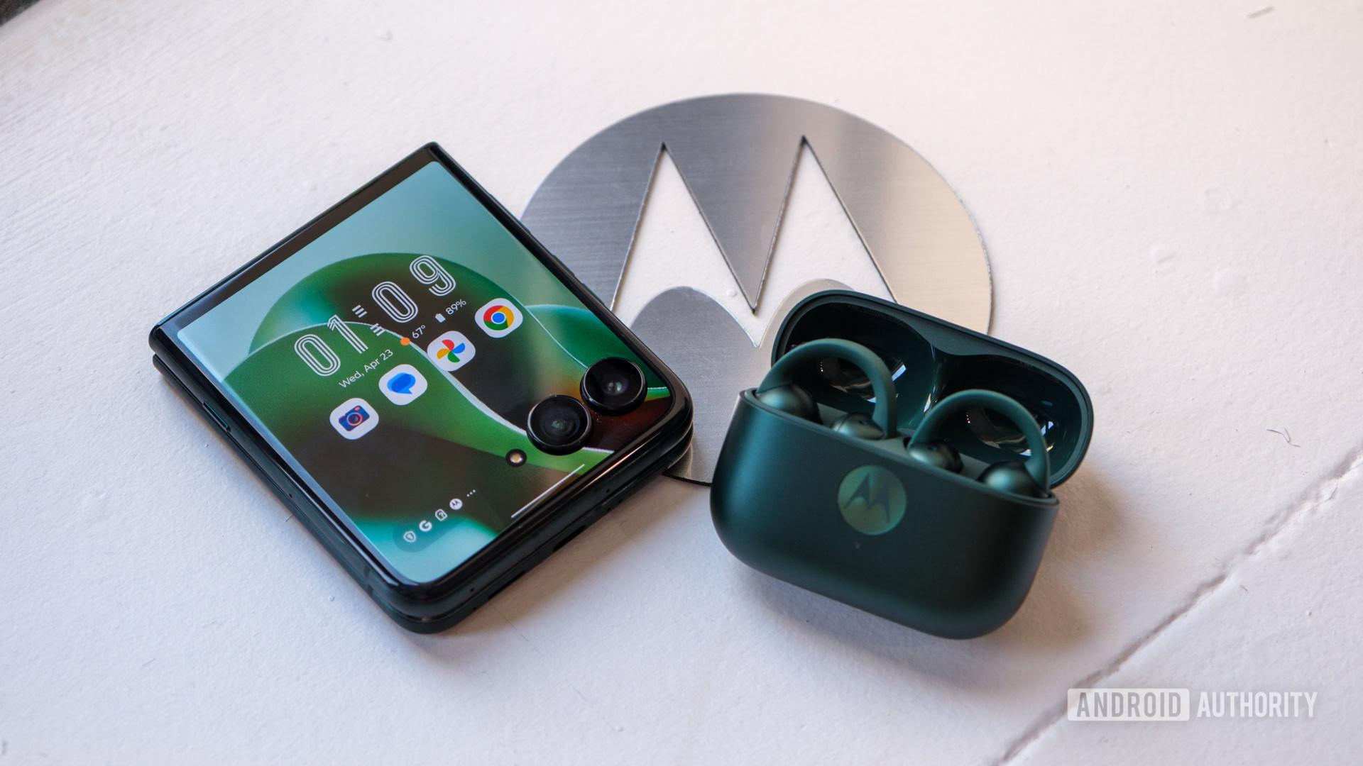 Motorola Razr Ultra with earbuds on top of logo Motorola Razr Ultra with earbuds on top of logo